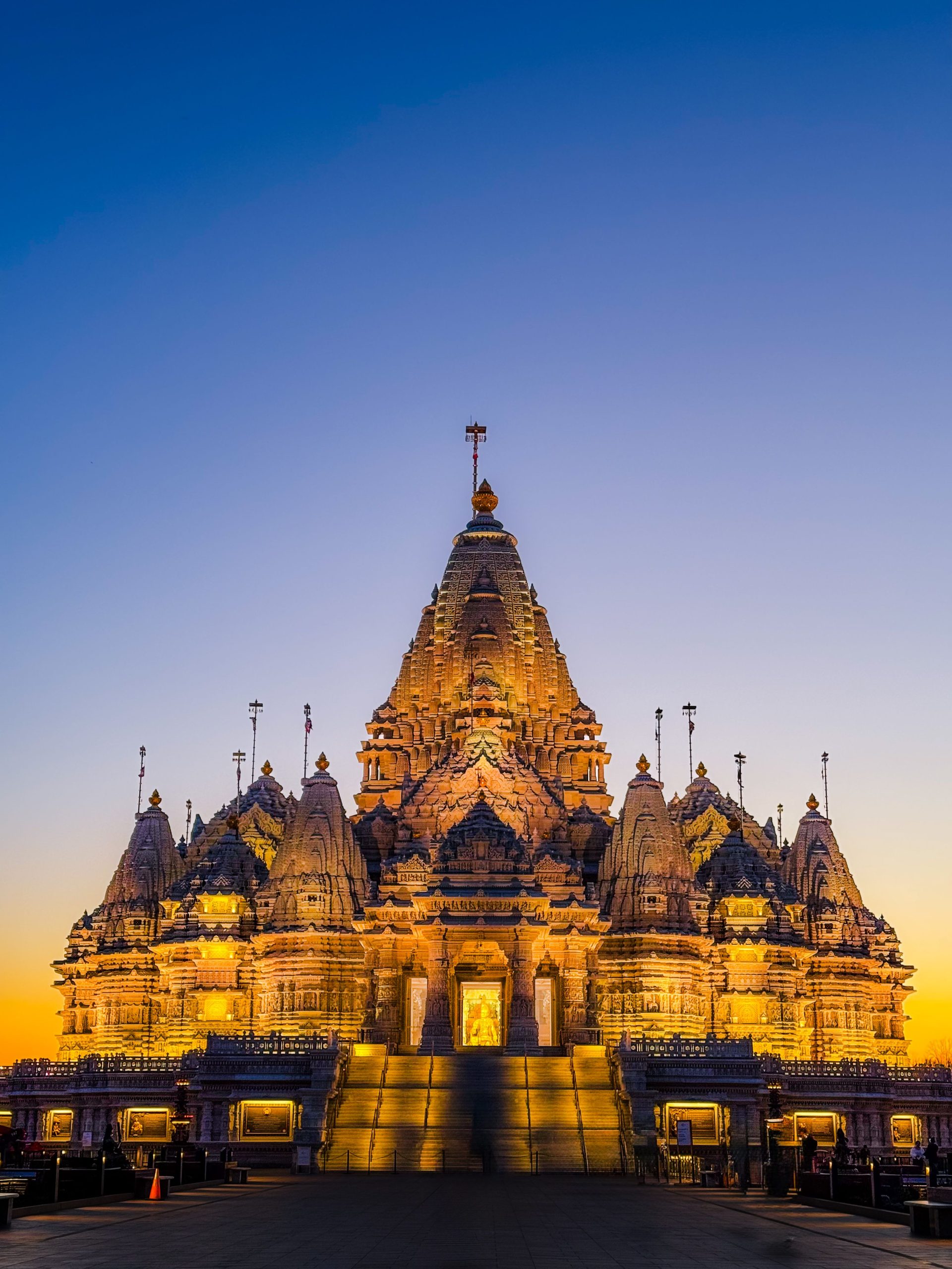 A beautifully illuminated Hindu temple under a vibrant twilight sky in East Windsor, NJ.